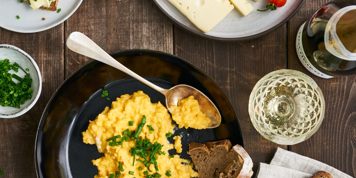 Pfanne mit Eierspeies und einem Glas Hochriegl Trocken auf rustikalen Holztisch