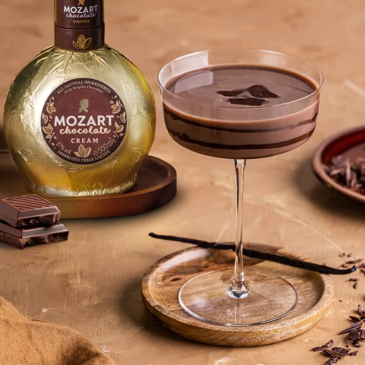 Mozart Cream Chocolate Likör mit Martini Glas und Schokolade auf einem Holztisch