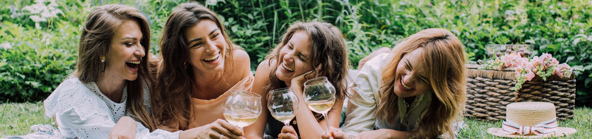 Vier Damen liegen auf einer Picknick Decke und trinken Goldeck Sekt
